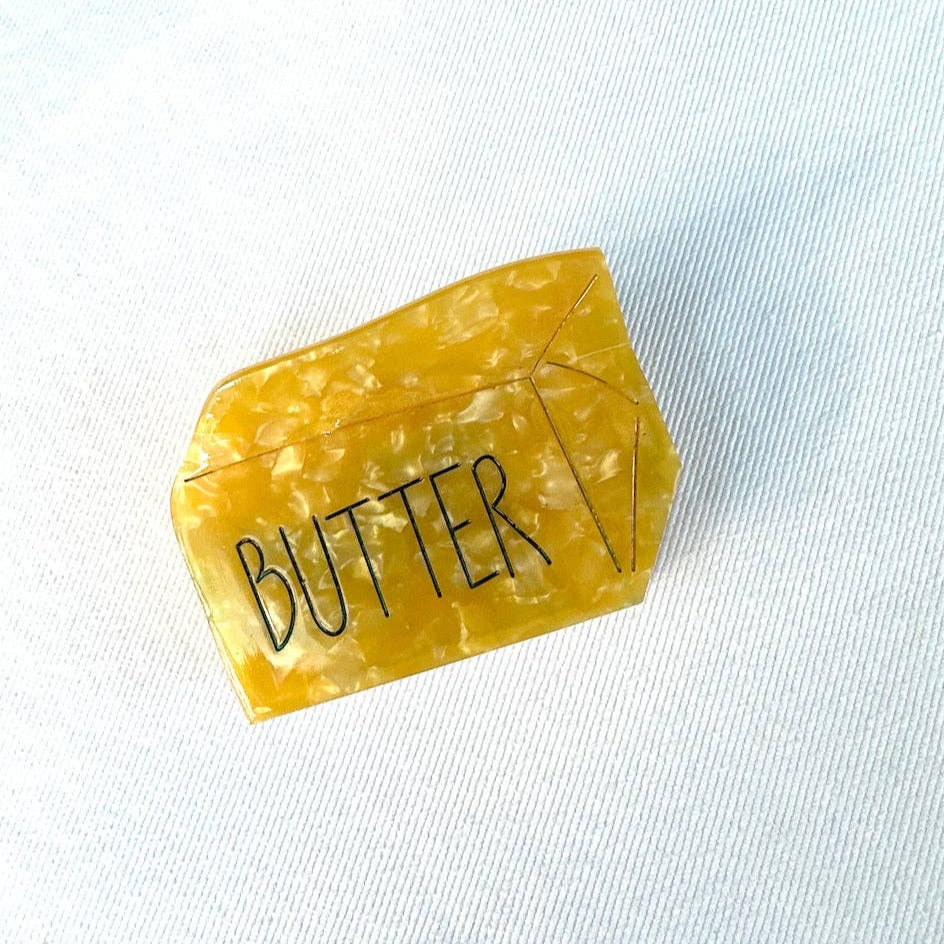 Stick of butter hair clip -- made of cellulose acetate, yellow with black text that reads "butter"