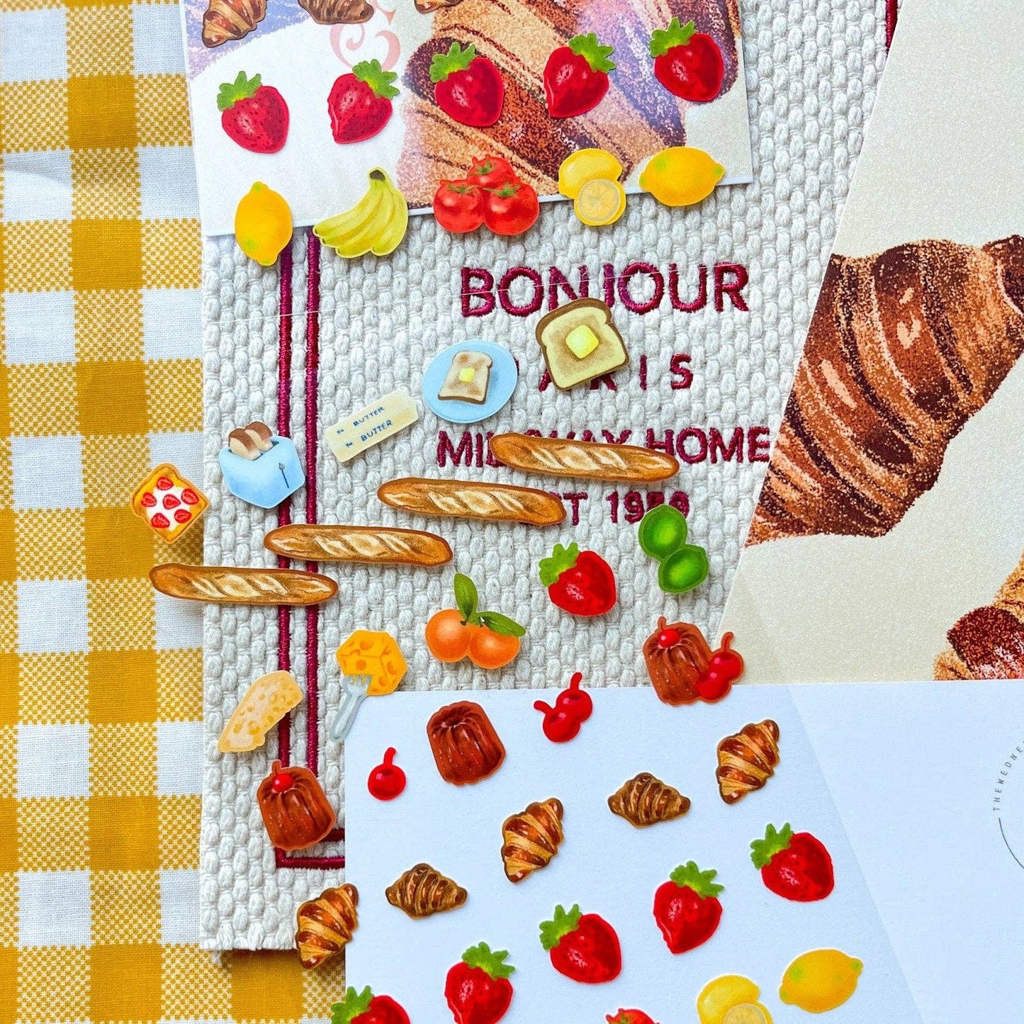 Sticker sheet with various fruits and types of bread on it -- includes but not limited to: strawberries, lemons, bananas, toast, butter, baguettes, croissants and caneles.