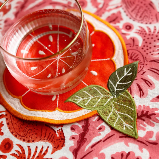 Orange slice coaster/cloth cocktail napkin with a water glass on it 