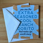Card with blue text on a white envelope featuring a humorous message, "you are the extra seasoned cool ranch dorito that makes life worth living" on a wooden surface.