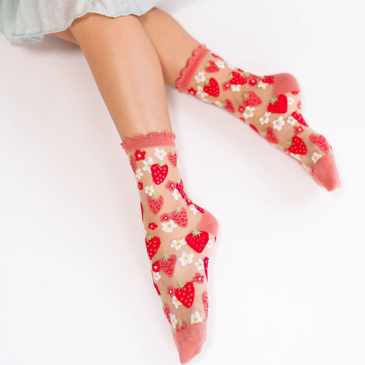 Pink and red strawberry patterned sheer crew socks on model 