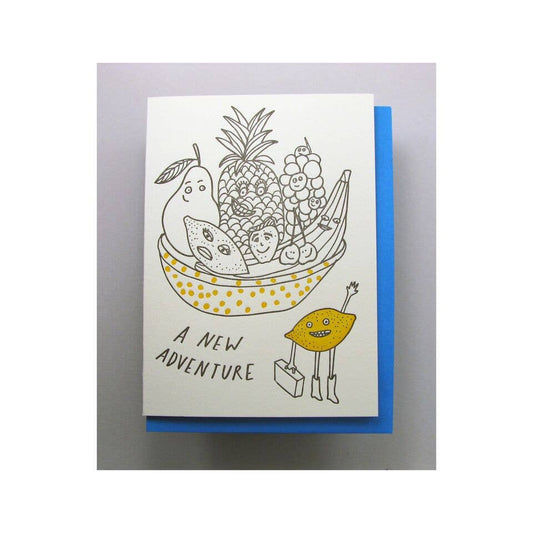 Greeting card with various fruits in a basket and a lemon holding a suitcase. Text reads "A new adventure" 