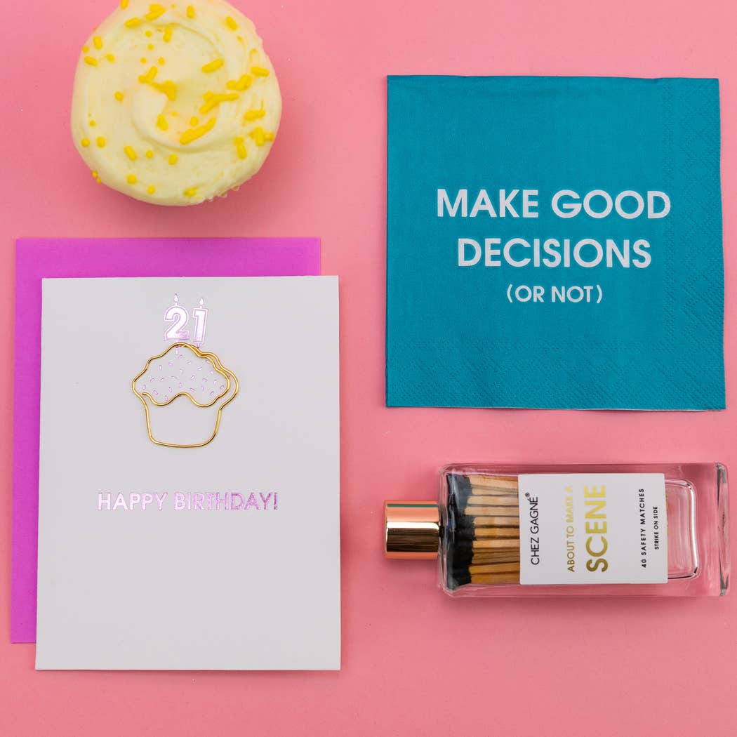 Perfume bottle, birthday card, cupcake, and motivational napkin on a pink background