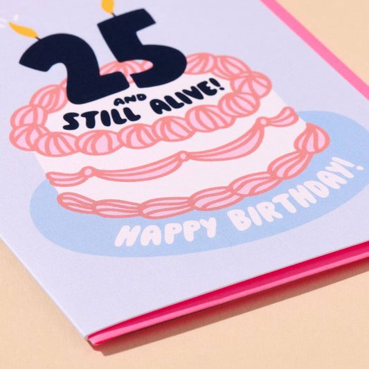 Birthday card with a cake illustration and text '25 and still alive! Happy Birthday!' on a light blue background.