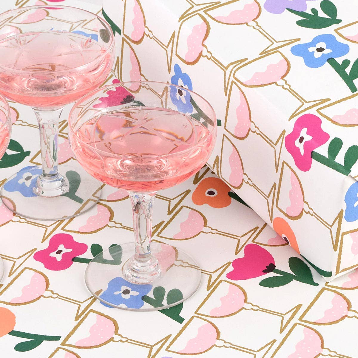 Two glasses of pink drink on a floral-patterned gift wrap 