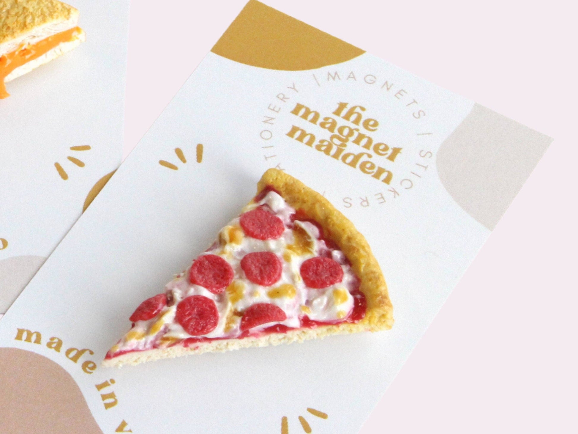 Handmade magnet shaped like a single slice of pepperoni pizza. Shown with printed backing label.