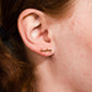 Single 14k gold plated stud earring -- reads "dumpling" in handwritten script. Shown on ear for scale 