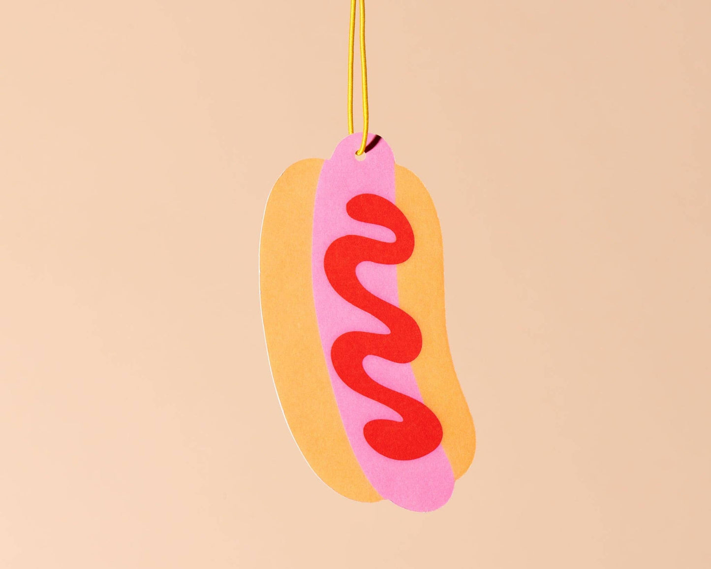 Hot dog shaped air freshener with ketchup on it. 