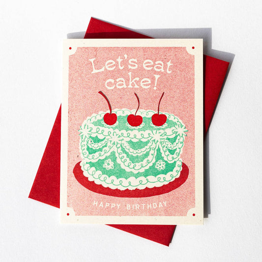 Birthday card with green frilly cake, decorated with ribboned icing and three red cherries on the top. Text reads "Let's eat cake! Happy birthday" 