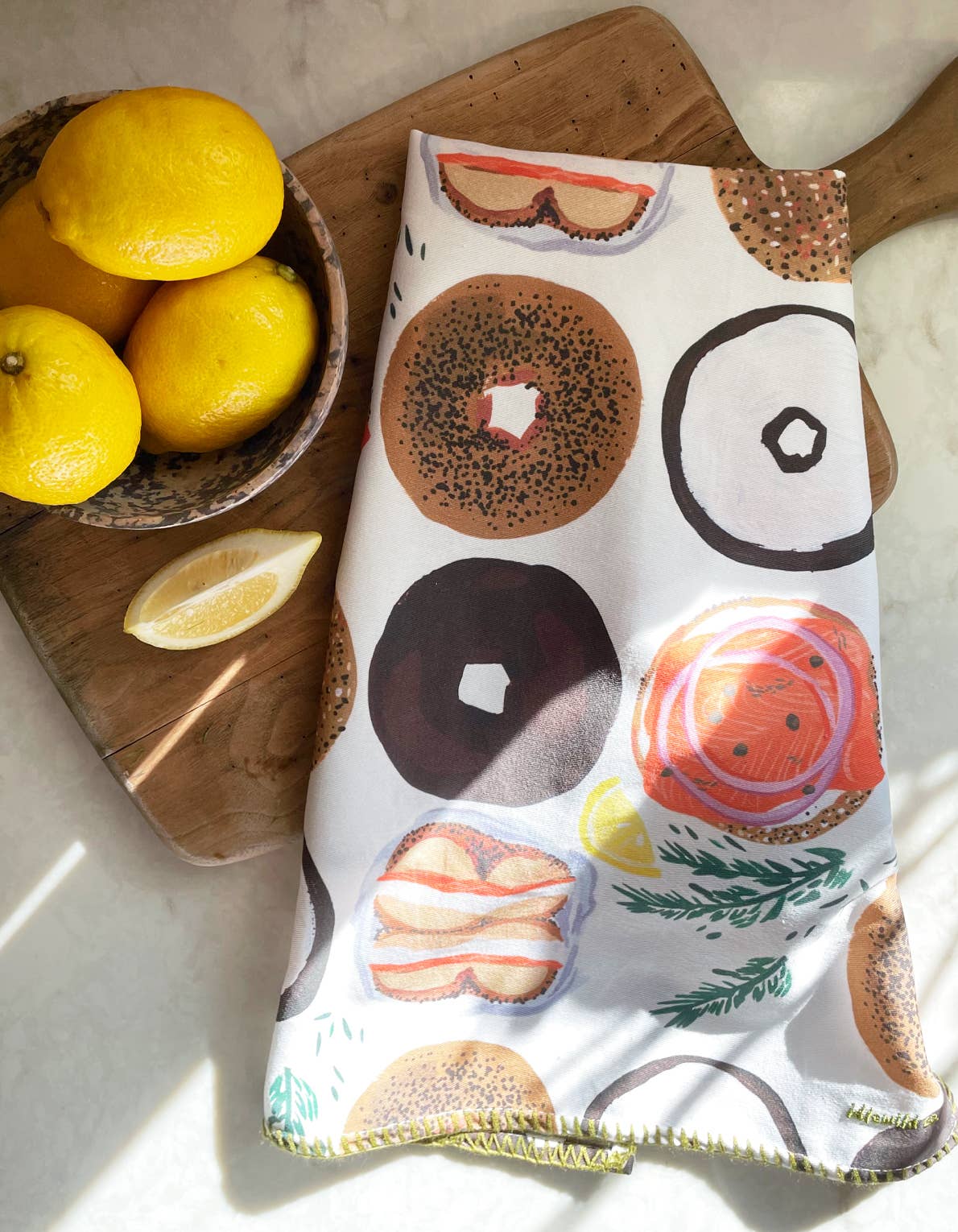 Bagel tea towel on cutting board next to a bowl of lemons 