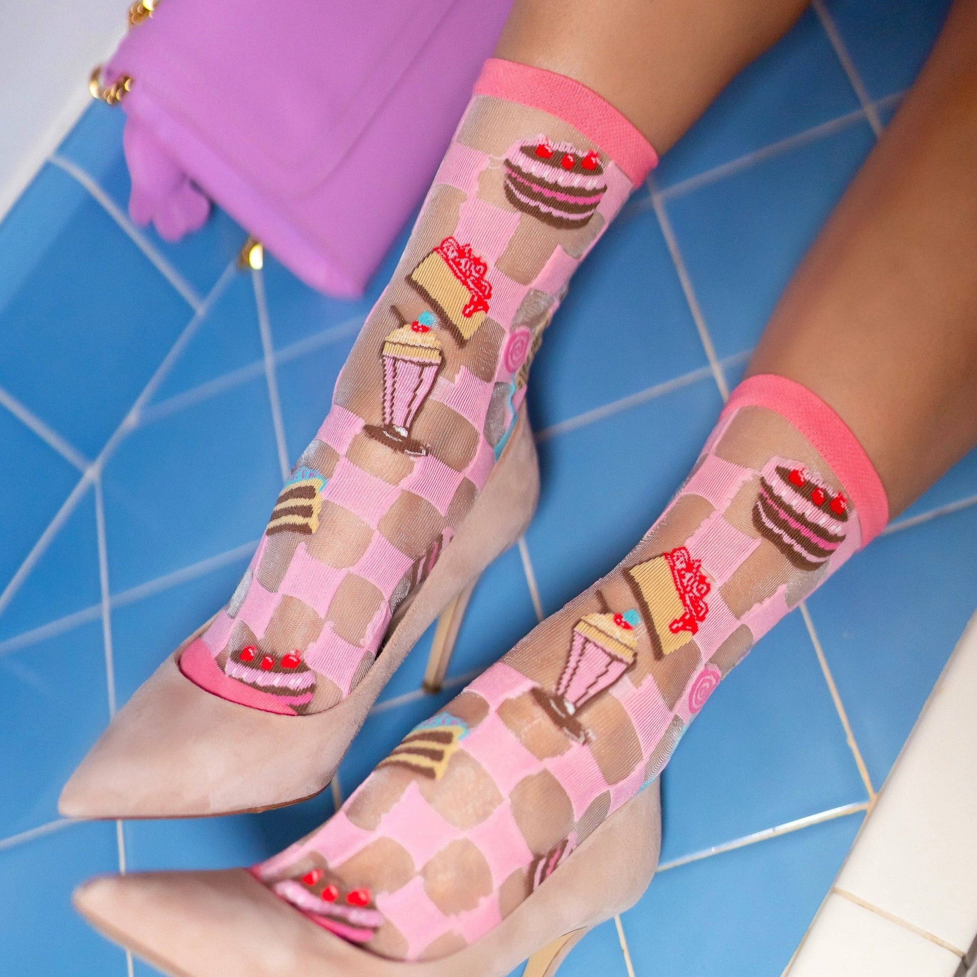 Pink, sheer, women's socks on model -- socks have cakes, ice cream, milkshakes and candy on them 