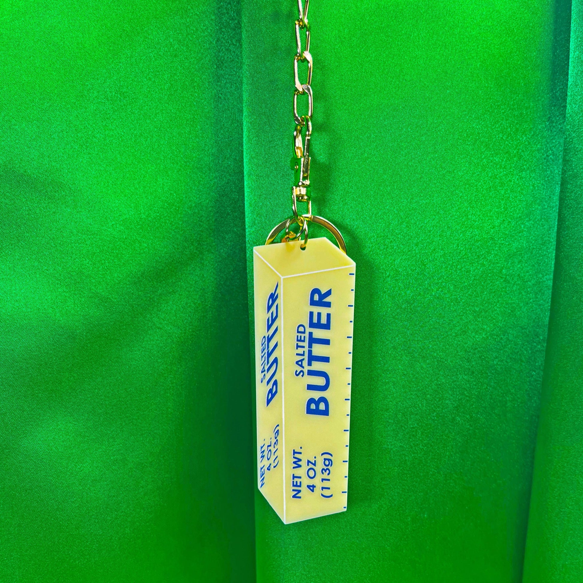 Keychain that looks like a stick of salted butter hanging from chainlinks 