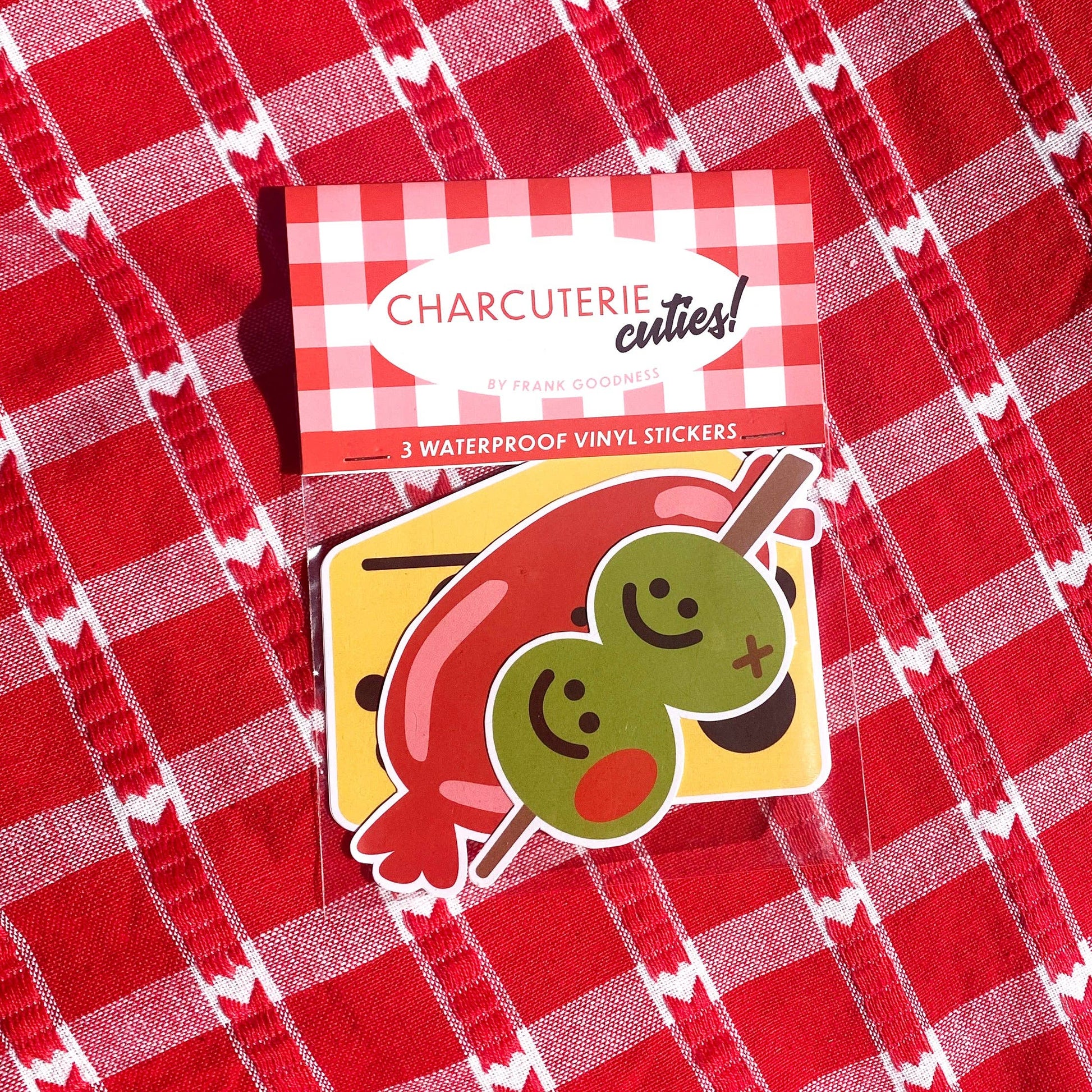 Charcuterie Cuties stickers in a pack laying on top of a table cloth.