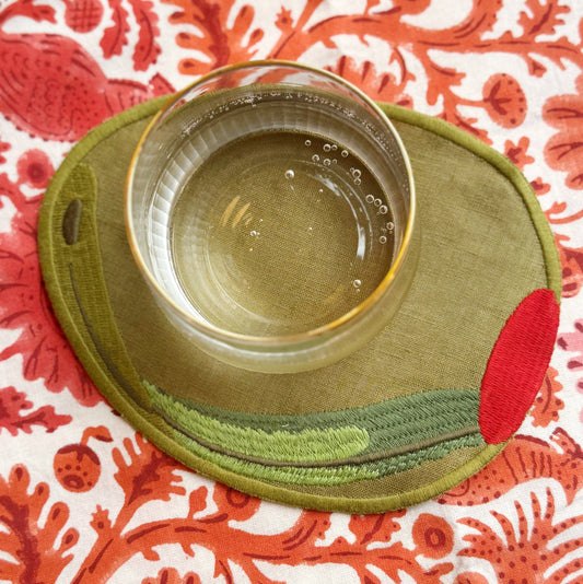 Stuffed green olive cloth napkin on table with a drink on top of it 