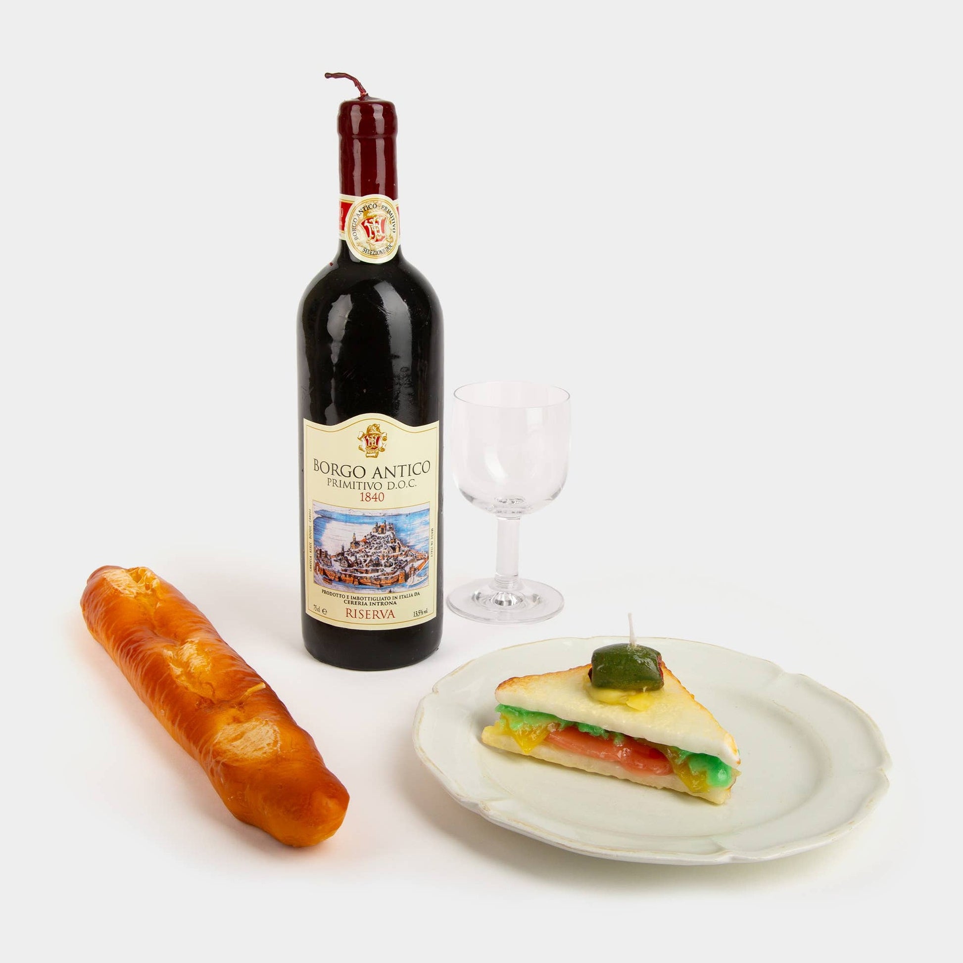Ensemble of wax candles shaped like a realistic wine bottle, baguette, and sandwich.