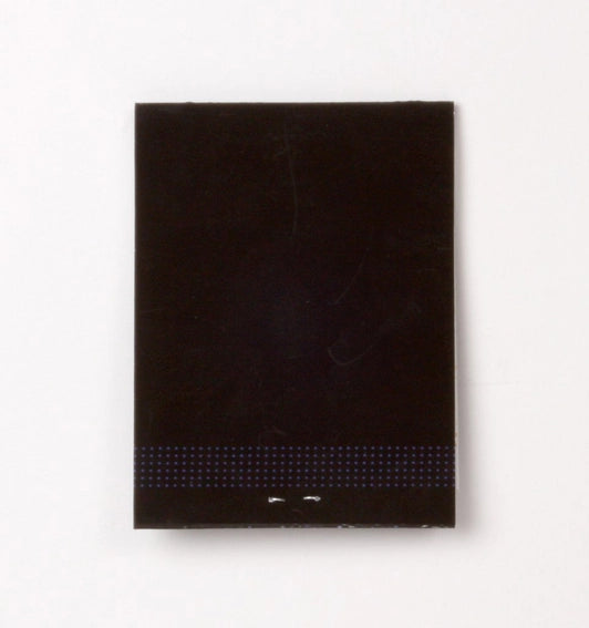Photo showing back of greeting card, black with subtle dots design (mimicking match striking area) toward the bottom.