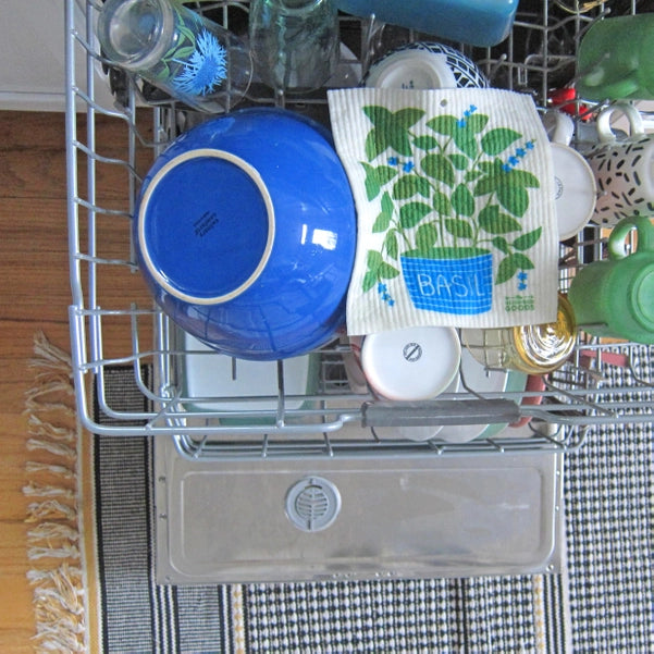 Photo of basil sponge cloth next to a blue bowl inside an open dishwasher.