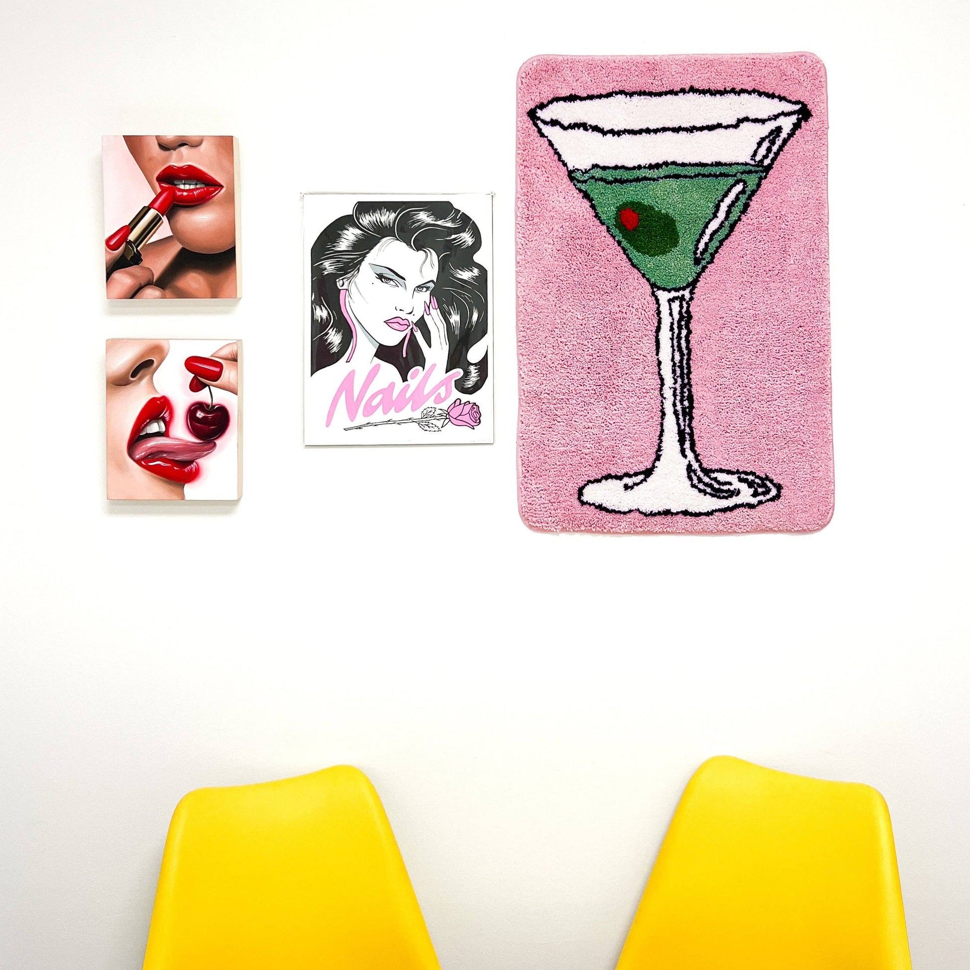Pink rug with a martini on it, hanging on a wall next to some prints 