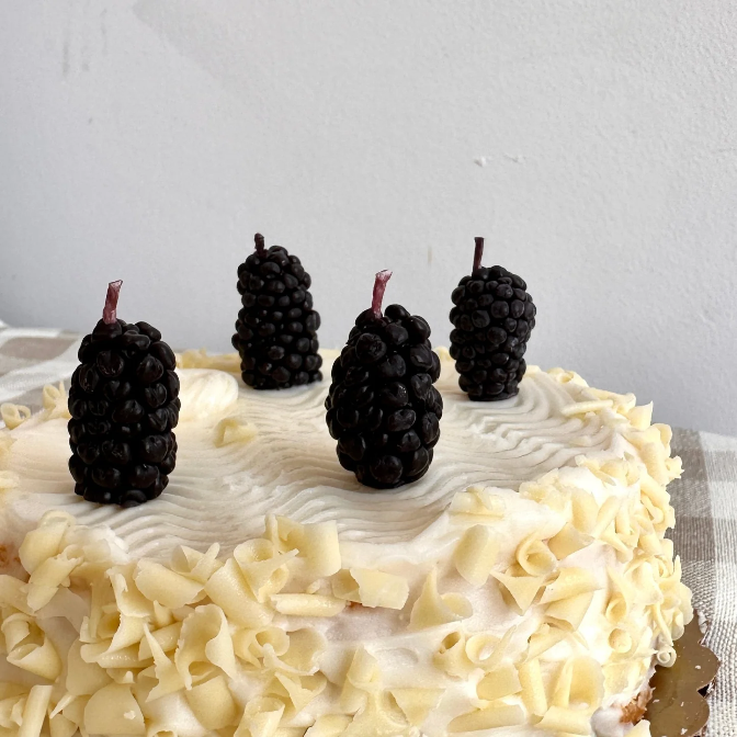 Four blackberry candles on cake 