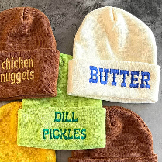"Butter" beanie shown next to "chicken nuggets" beanie and "dill pickles" beanie.