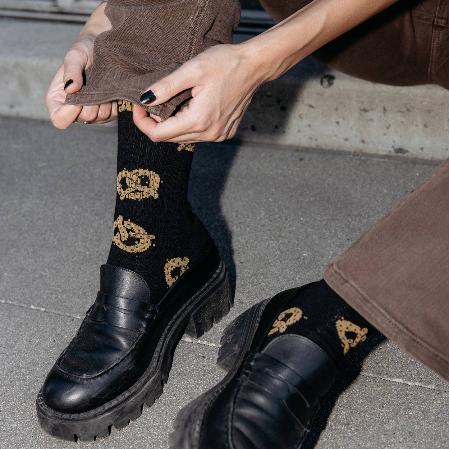 Model wearing pretzel socks cuffing her pant as an action shot.