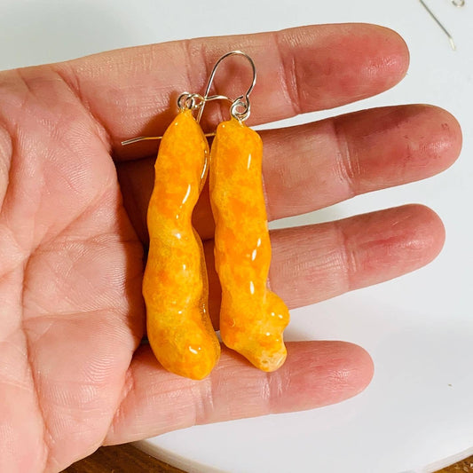 a pair of regular cheeto earrings, held in someone's hand 
