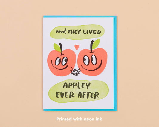 Greeting card with two apples holding hands and text that reads "and they lived appley ever after" 