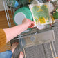 Photo of dill sponge cloth next to green and yellow dishes in an open dishwasher.