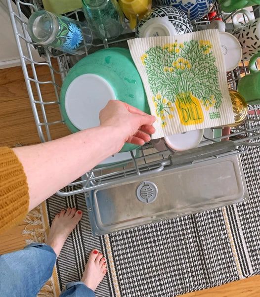 Photo of dill sponge cloth next to green and yellow dishes in an open dishwasher.