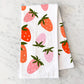 Folded, white kitchen towel with pink and red strawberries on it 