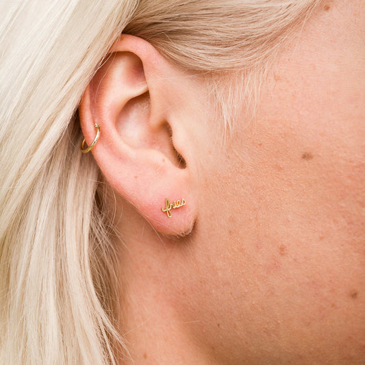 Single 14k gold plated stud earring -- reads "fries" in handwritten script. Shown on ear for scale 