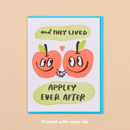 Greeting card with two apples holding hands and text that reads "and they lived appley ever after" 