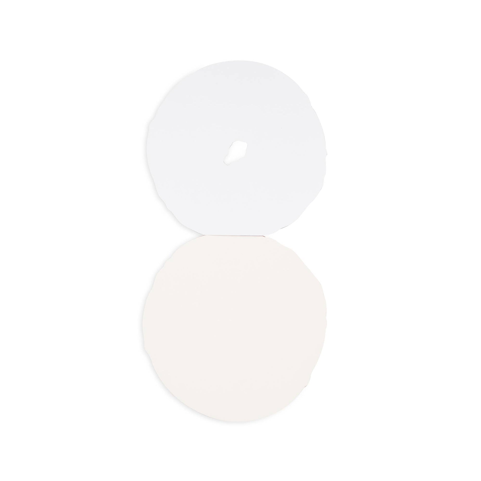 Two white circular objects on a light beige background. Interior shot of the bagel notepad showing blank pages.