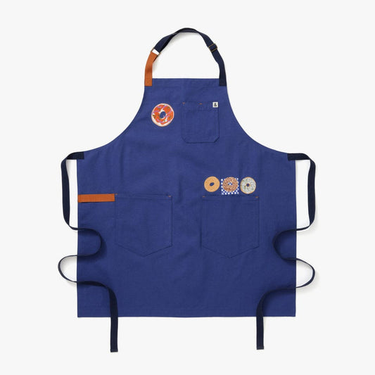 Blue apron with navy/black straps. This apron highlights 4 different styles of bagels. 