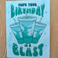 Greeting card with birthday message "hope your birthday is a blast" and soda cups of Baja Blast on a wooden surface