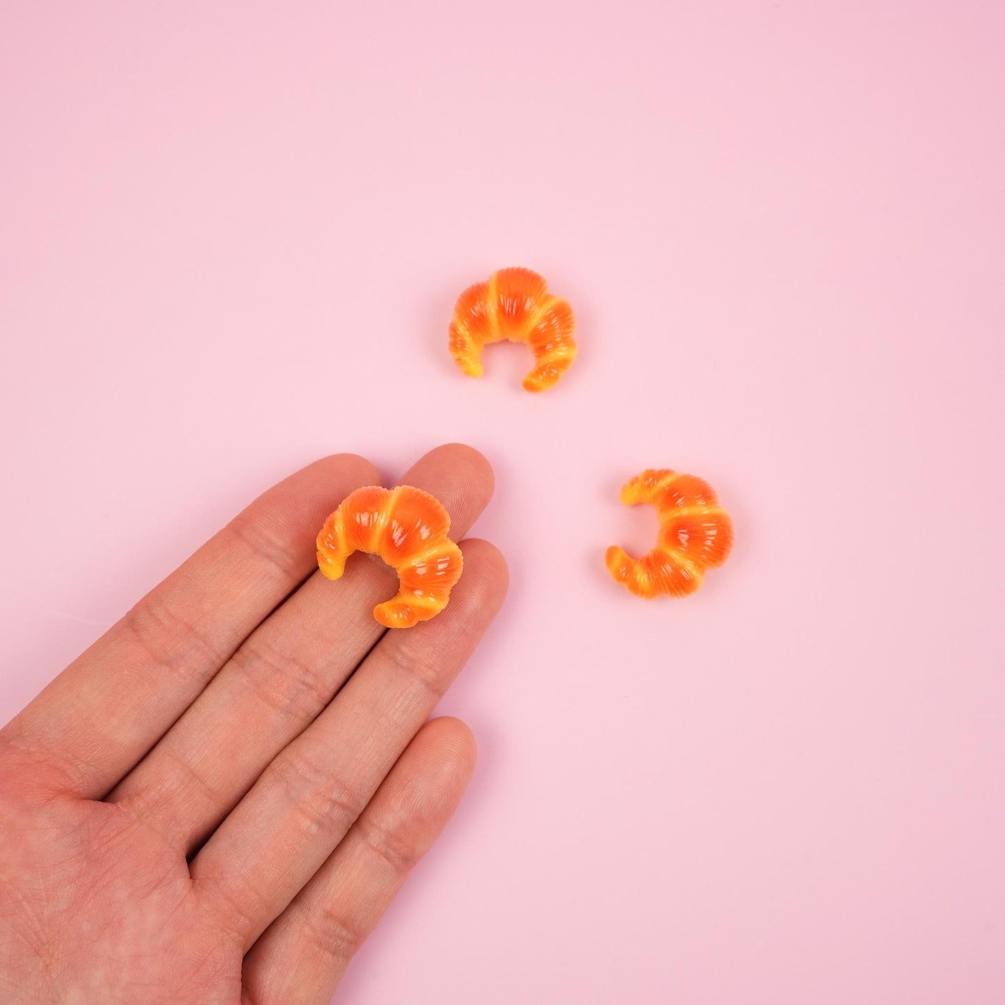 3 Croissant magnets and a hand is holding one.