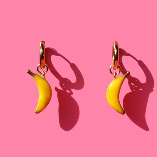 Banana-shaped earrings on a pink background
