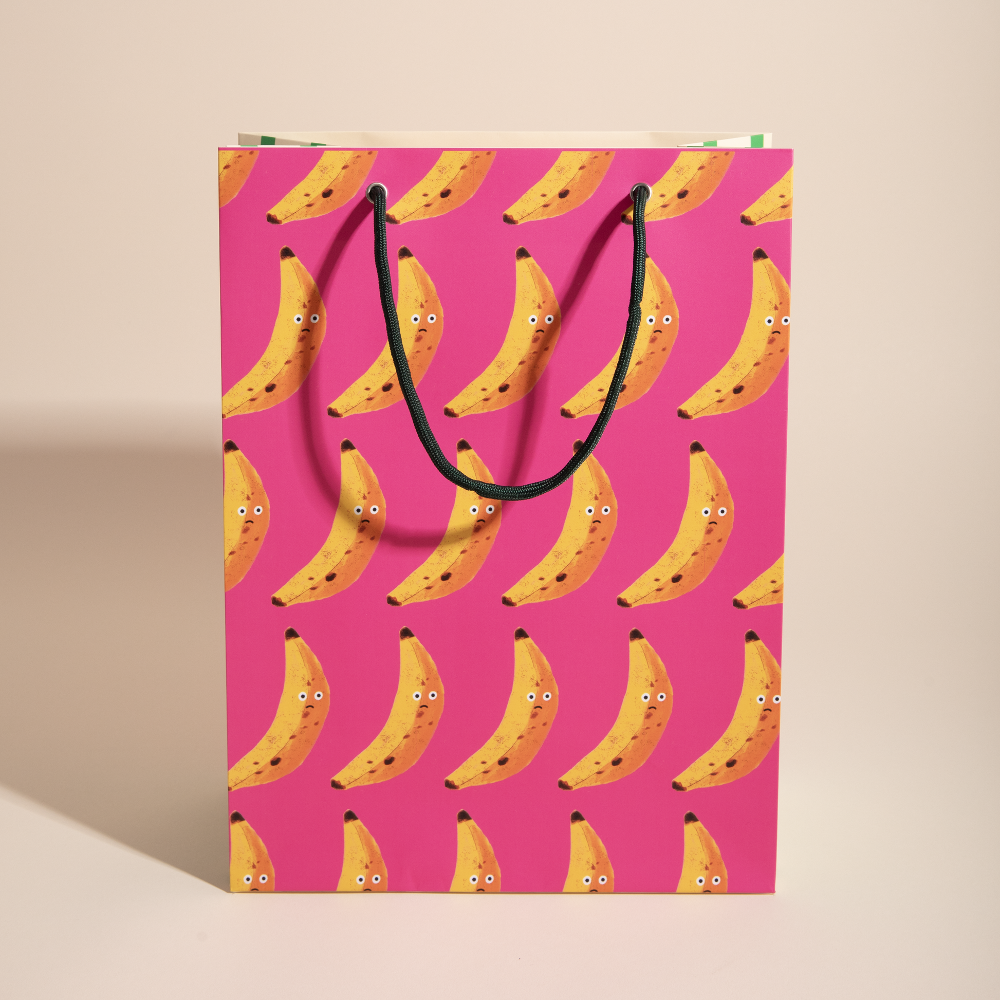 matte gift bag with grumpy face banana pattern on a pink background
