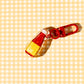 Back view -- Decorative charm shaped like a bottle of Banana Ketchup. Red bottle with text "i'm fuckin' yummy" on yellow label.