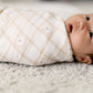 Baby wrapped in a patterned swaddle on a soft surface