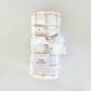 Plaid baby swaddle with a white bow on a light gray background