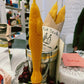 Single yellow beeswax taper candle shaped like a fish. Shown unwrapped on countertop.