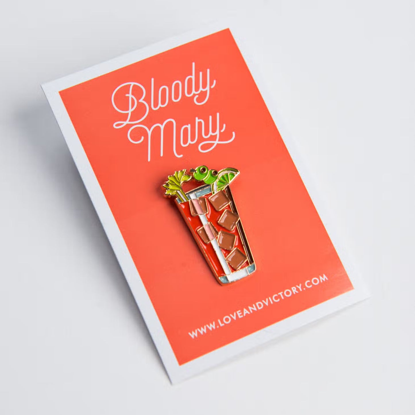 Bloody Mary lapel pin on red card backing.