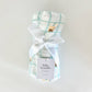 Baby swaddle with plaid pattern and cartoon design, tied with a white ribbon on a light gray background.