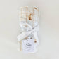 Baby swaddle with plaid pattern and white ribbon on a light gray background