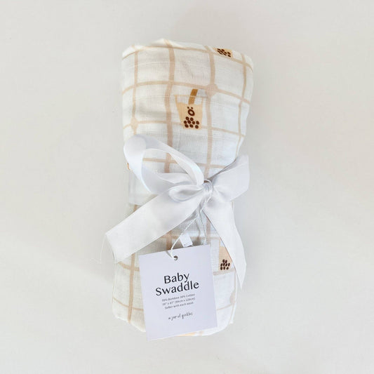 Baby swaddle with plaid pattern and white ribbon on a light gray background