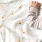 Close-up of a baby's hand reaching through a textured blanket with paw print patterns.