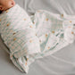 Newborn baby swaddled in a soft blanket with a grid pattern on a neutral background