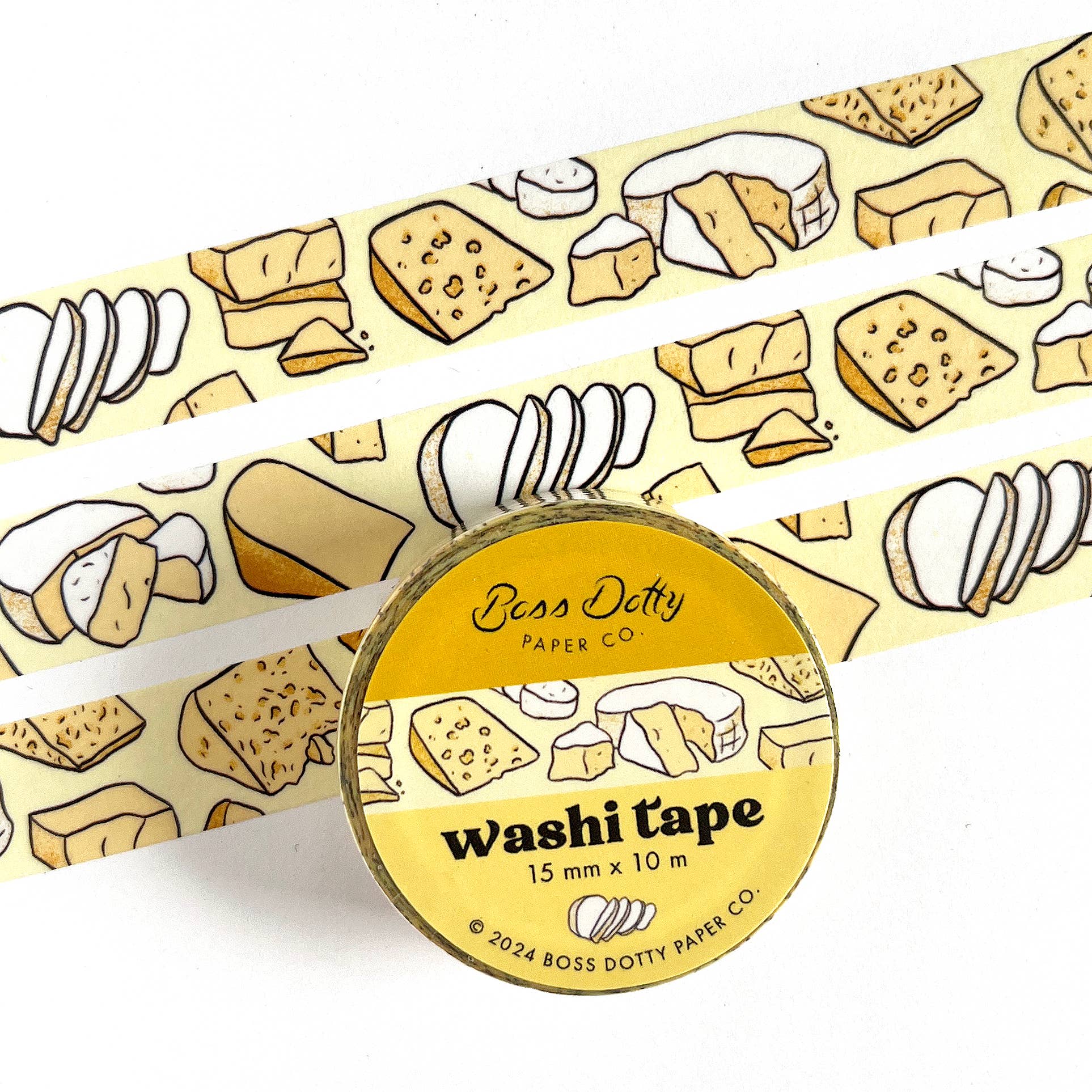 Washi tape featuring a pattern of different cheeses. 3 strips of tape laid out for display and one roll in its whole form.