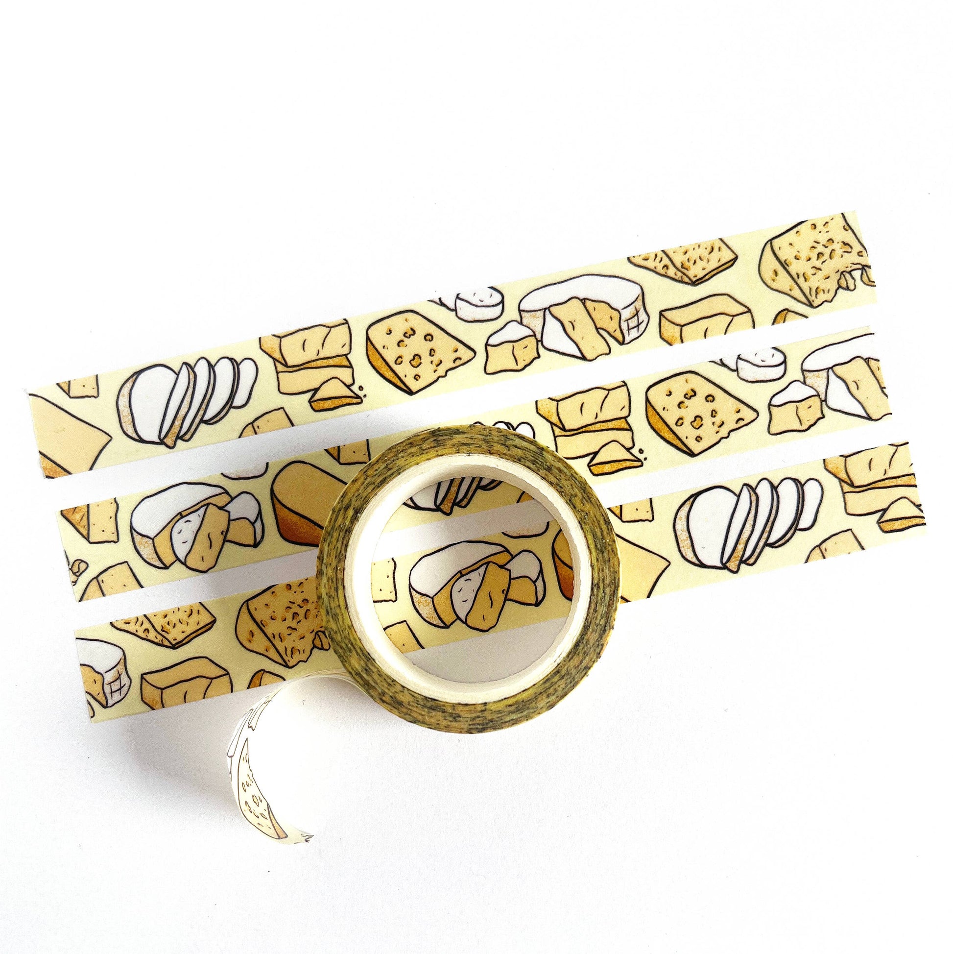 Washi tape featuring a pattern of different cheeses. 3 strips of tape laid out for display and one roll in its whole form.